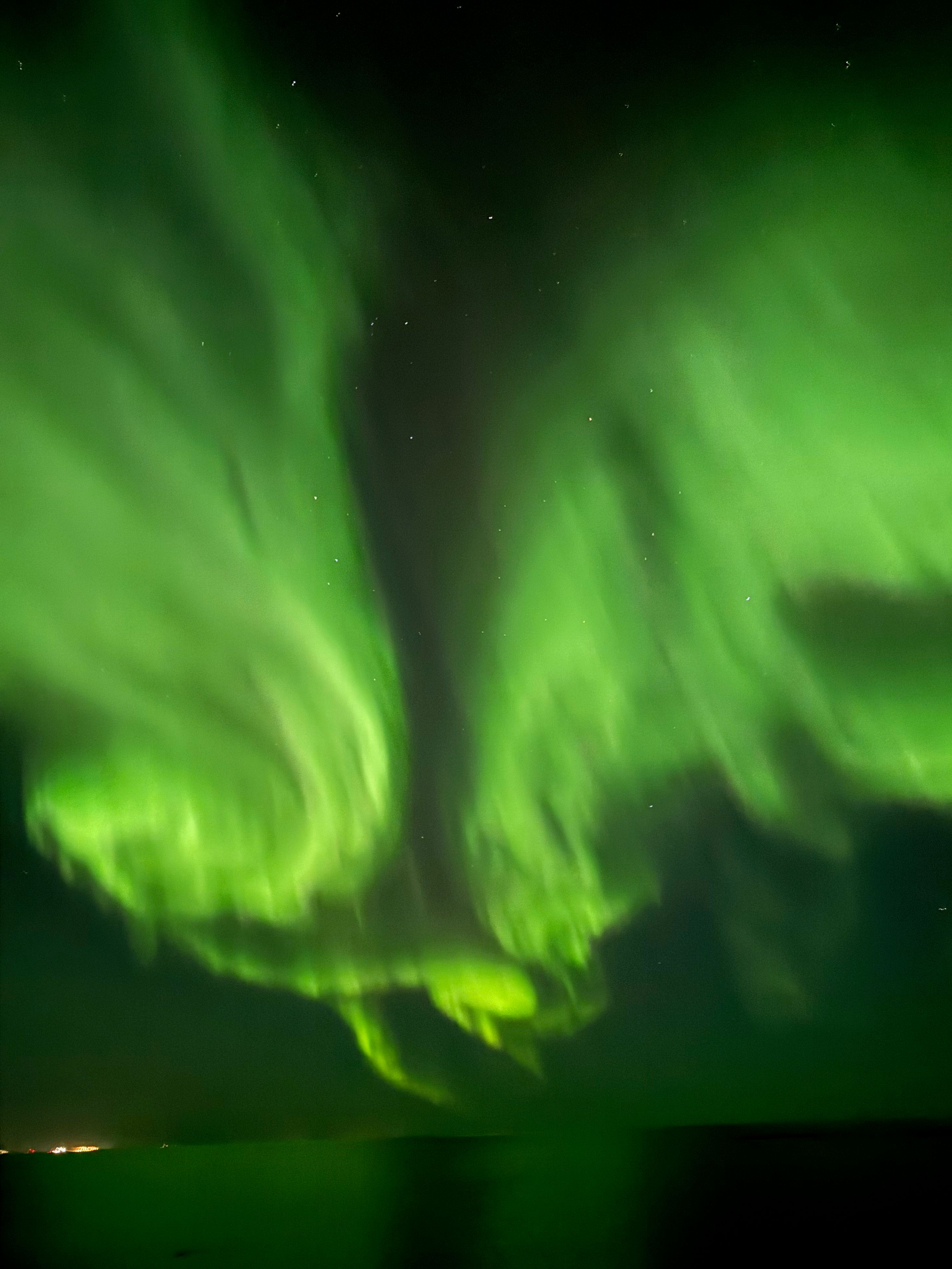 Swirling green lights over a glassy sea